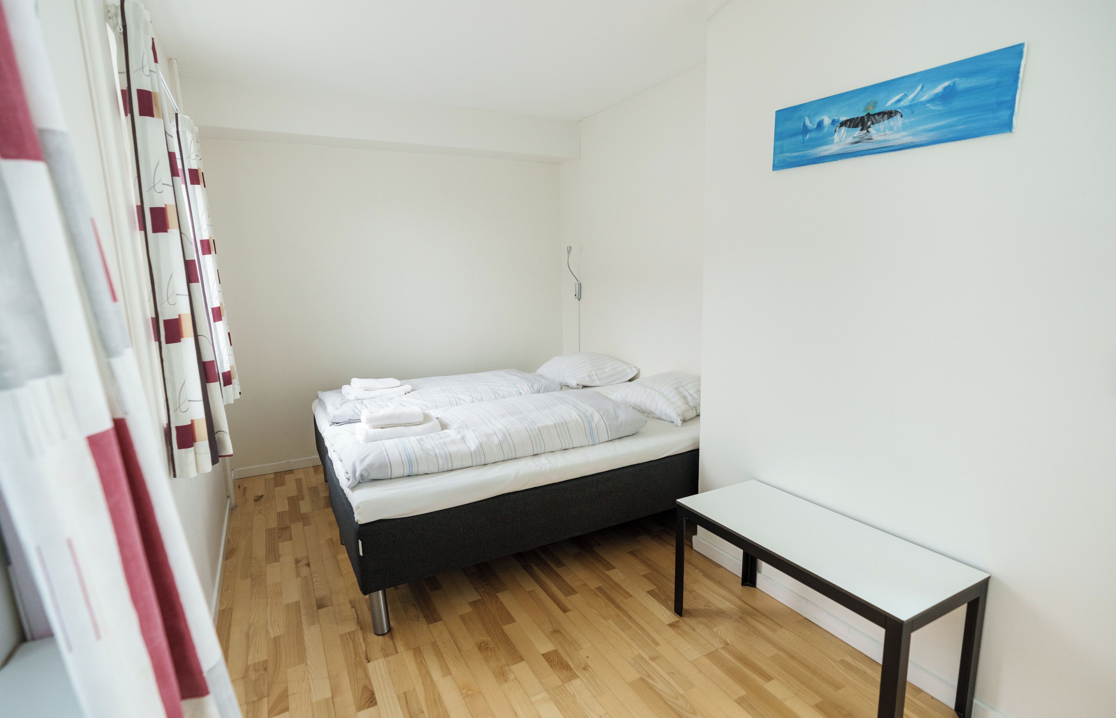 Ein Schlafzimmer mit einem Bett, einem Nachttisch, einer Wandleuchte und einem Bild.