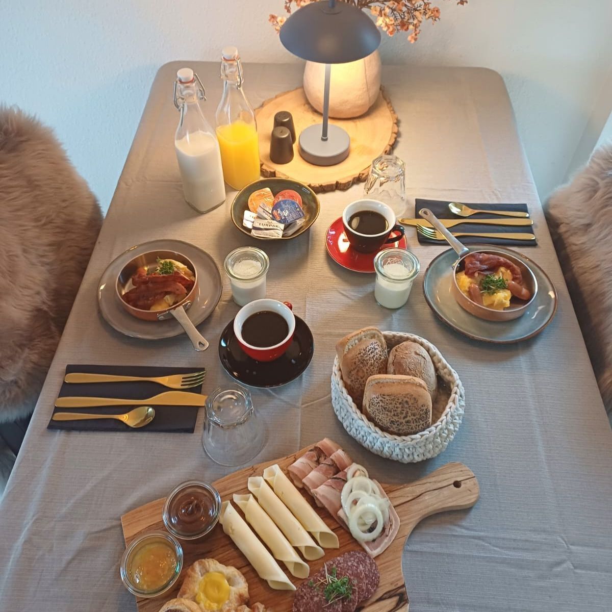 Ein Frühstückstisch mit verschiedenen Speisen, darunter Brot, Gebäck und Würzmitteln.