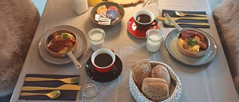Ein Frühstückstisch mit verschiedenen Speisen, darunter Brot, Gebäck und Würzmitteln.
