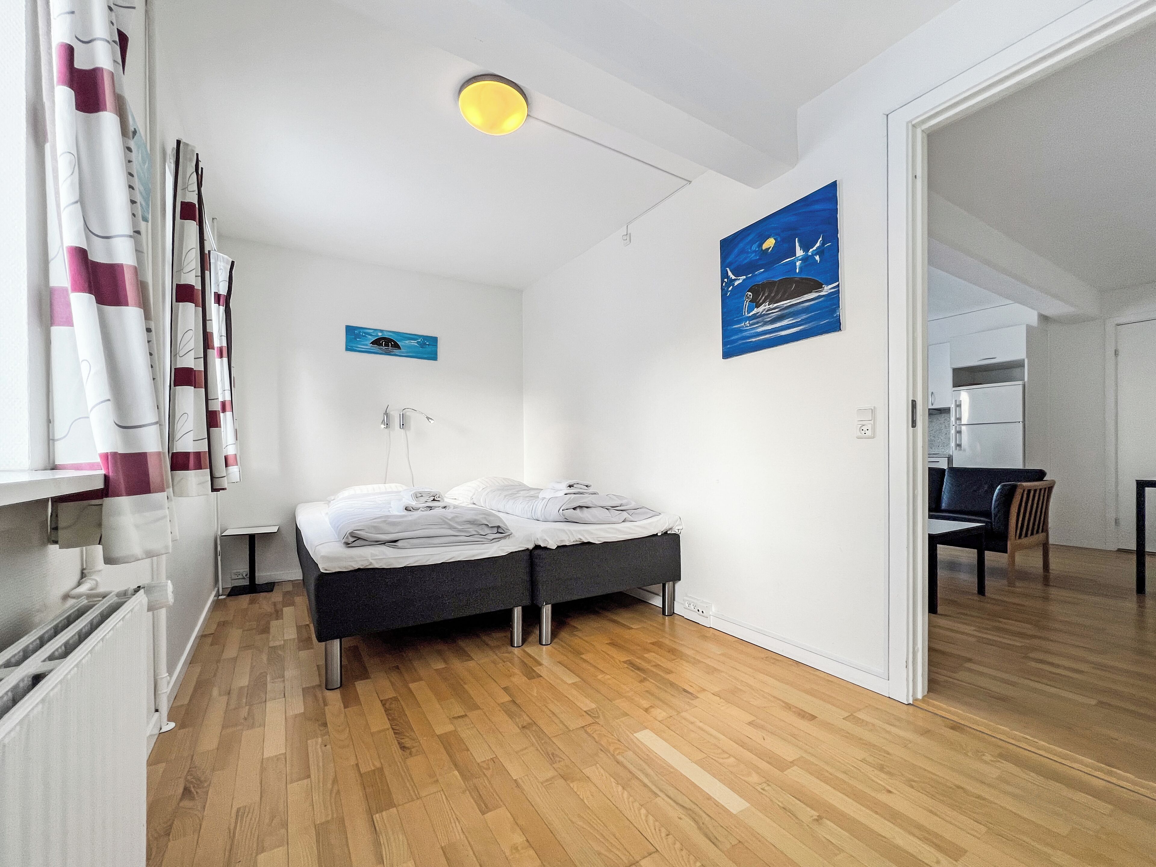 A modern hotel room with a bed, a desk, and a view of the kitchen.