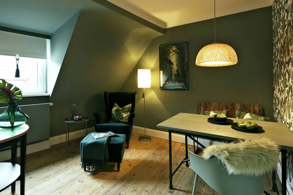 A dining area with a table, chairs, a lamp, and a poster on the wall.
