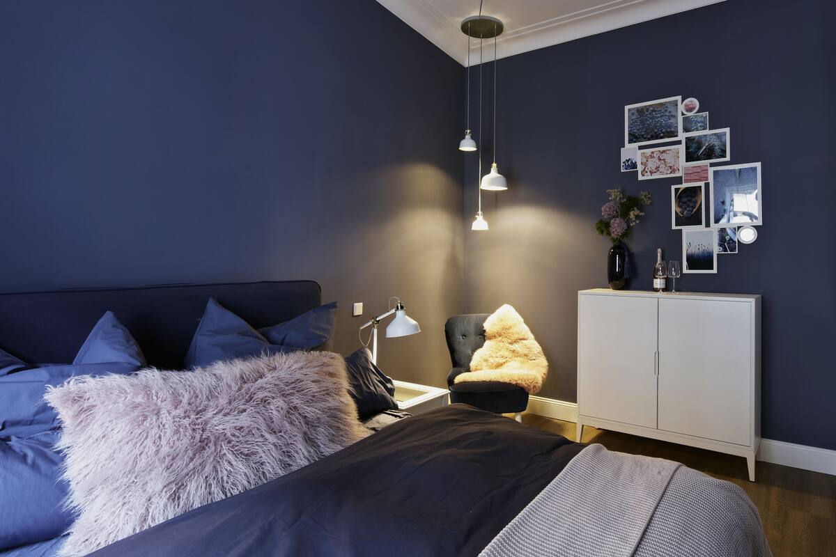 A bedroom with a bed, a chair, a desk, and a cabinet.