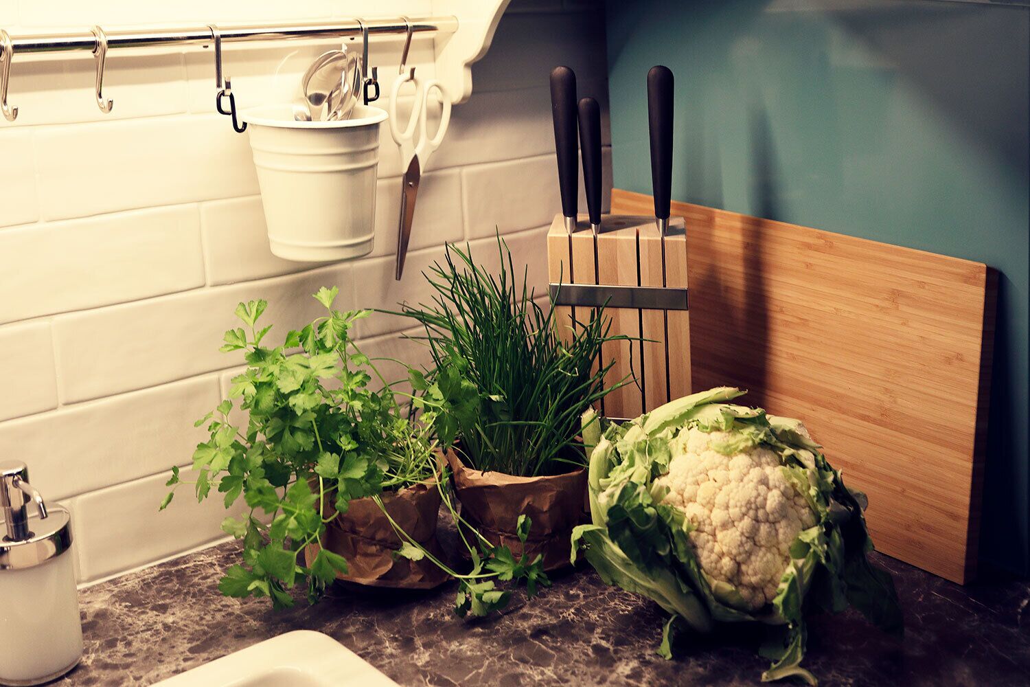 Uma bancada de cozinha com legumes frescos, tábua de corte e utensílios de cozinha.