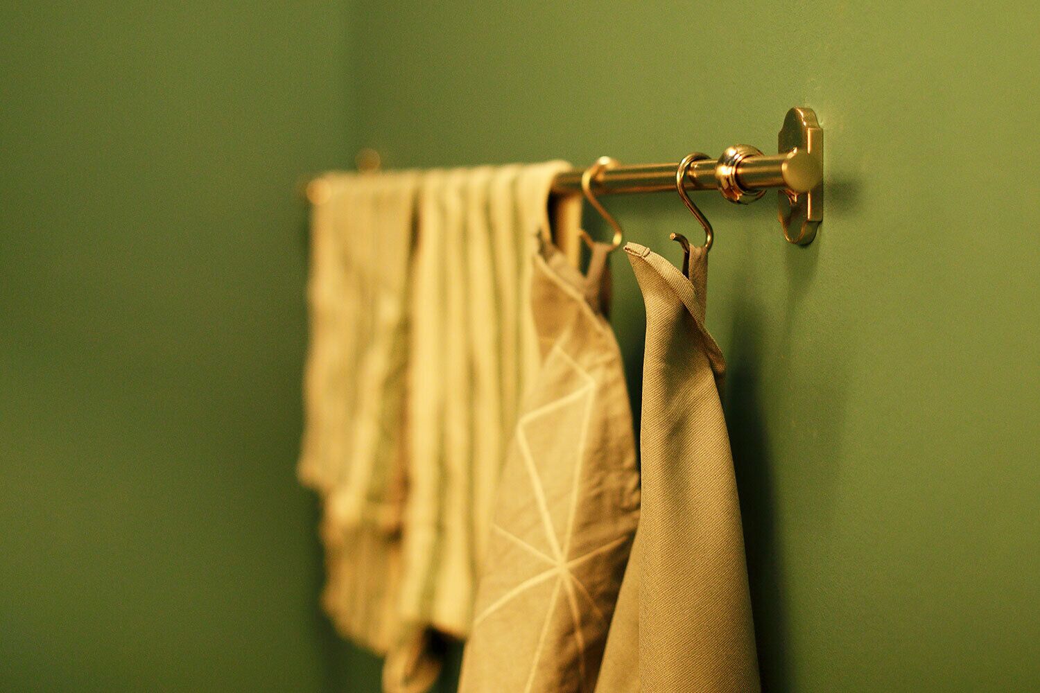 A bathroom with a green wall and a towel rack holding several towels.