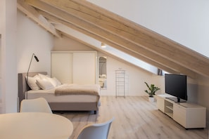 Un dormitorio moderno con cama, mesita de noche, televisor y una planta en maceta.