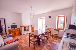 A spacious living area with a fireplace, dining table, and a kitchen area with a stove.