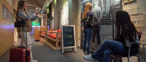 Un espace intérieur accueillant, avec des bancs en bois, une valise rouge et un tableau noir servant de menu.