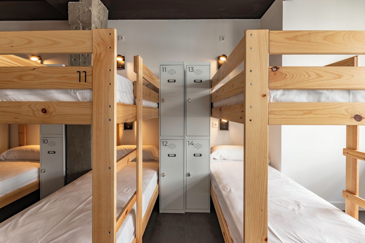 A bunk bed room with wooden bunk beds and metal lockers numbered 10 to 14.