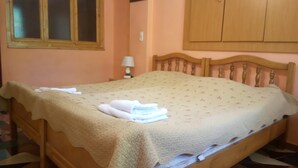 Une chambre à coucher avec un lit, une tête de lit en bois, une table de chevet avec une lampe et une armoire.