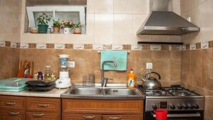 Une cuisine équipée d’un évier en acier inoxydable, d’une cuisinière et d’une fenêtre située au-dessus de l’évier, agrémentée de plantes en pot.
