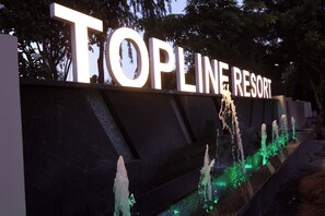 Schild für Topline Resort mit beleuchteten Buchstaben und einem Wasserspiel darunter.