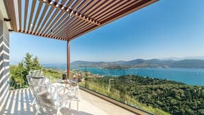 A balcony with a table and chairs overlooking a scenic view of a lake and mountains. - Katouna Suites Luxury Boutique Hotel - Adults Only (Lefkada)