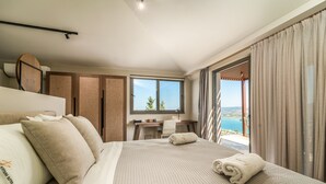 A hotel room with a large bed, a desk, and a view of the sea. - Katouna Suites Luxury Boutique Hotel - Adults Only (Lefkada)