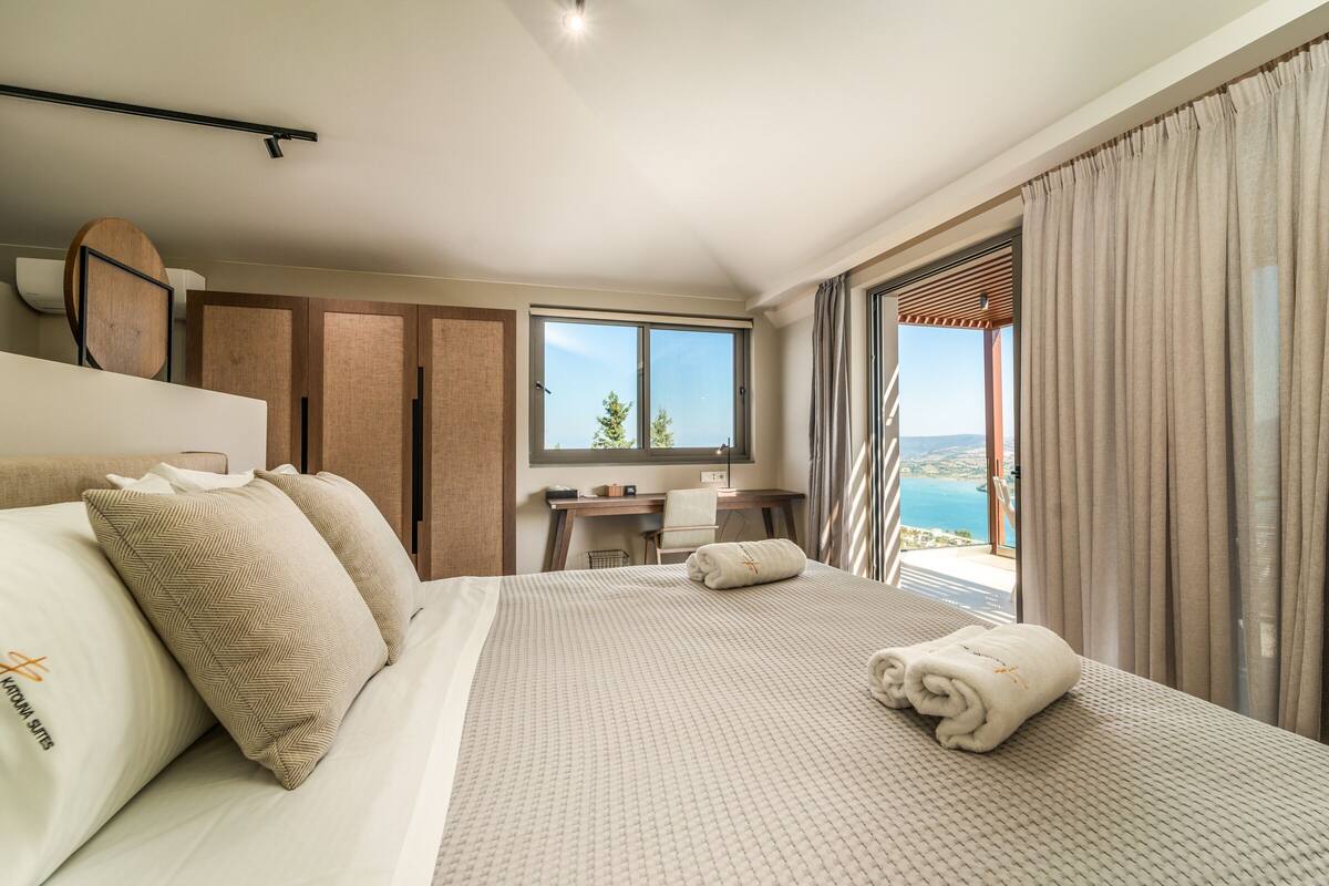 A hotel room with a large bed, a desk, and a view of the sea.