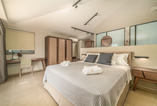 A modern bedroom with a large bed, a desk, and a wardrobe. - Katouna Suites Luxury Boutique Hotel - Adults Only (Lefkada)