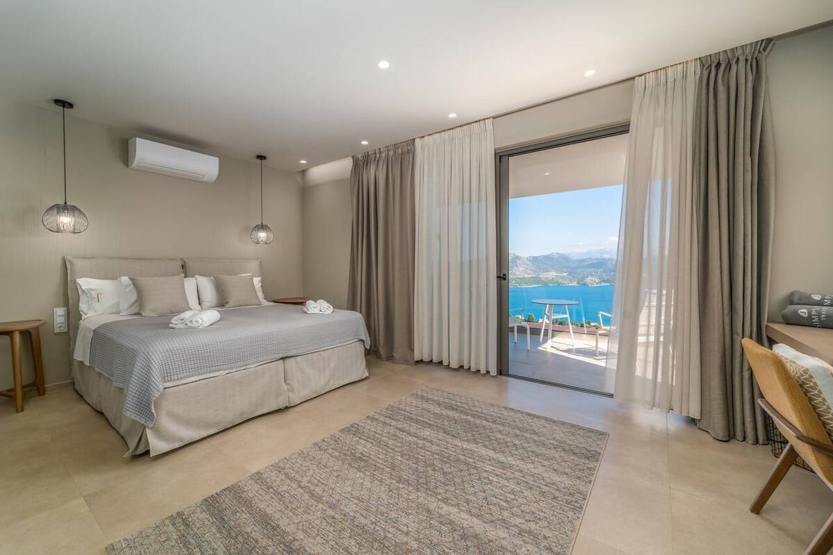 A bedroom with a large bed, a view of the sea, and a balcony.