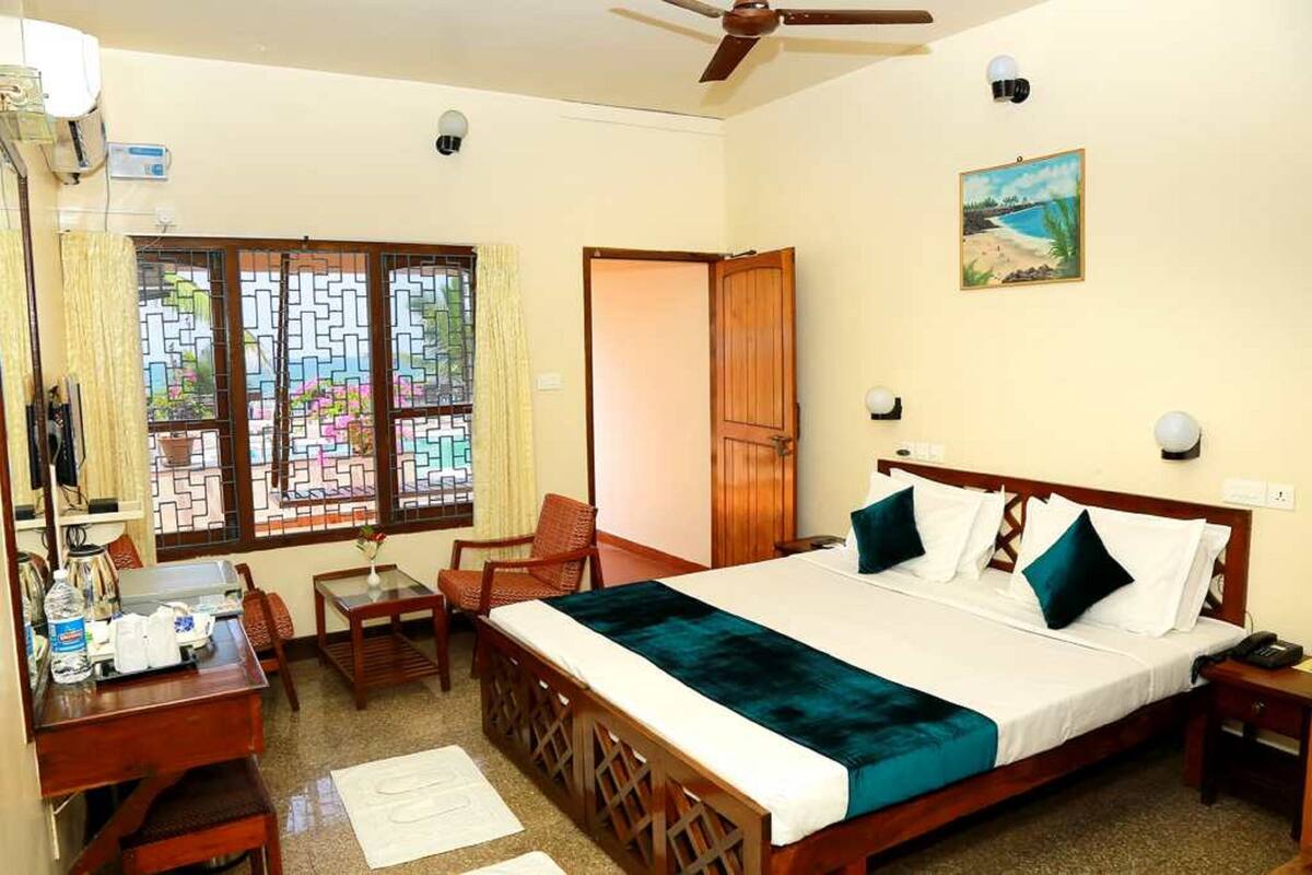 A hotel room with a bed, desk, chair, and a window with a view.