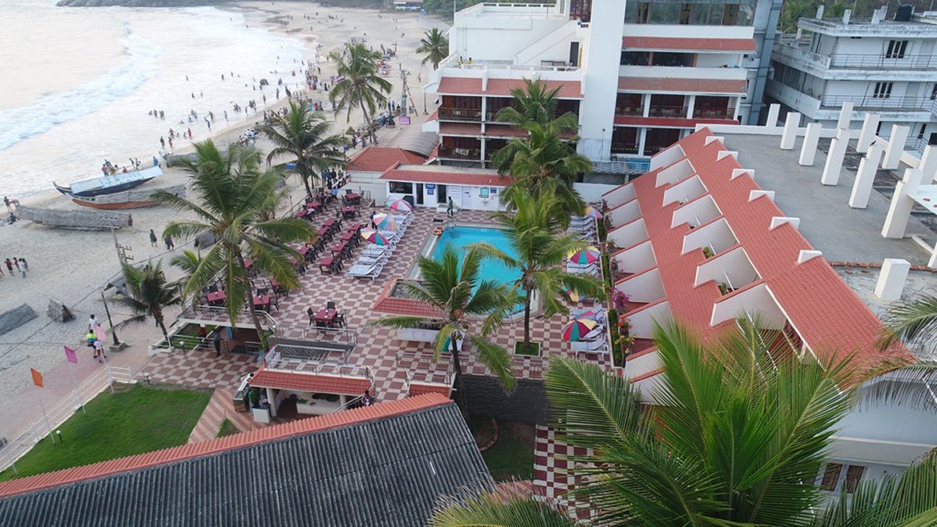 A hotel with a pool, beach access, and palm trees.