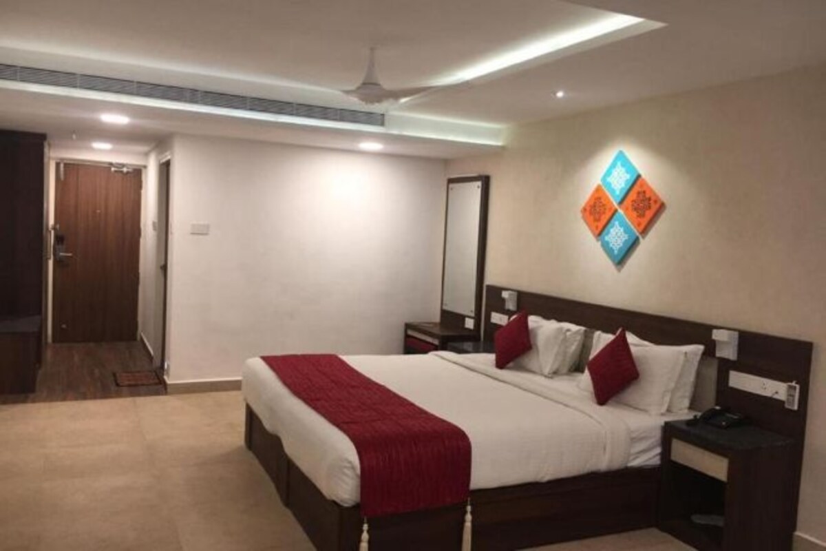Habitación de hotel con una cama grande, una mesita de noche, un espejo y un ventilador de techo.