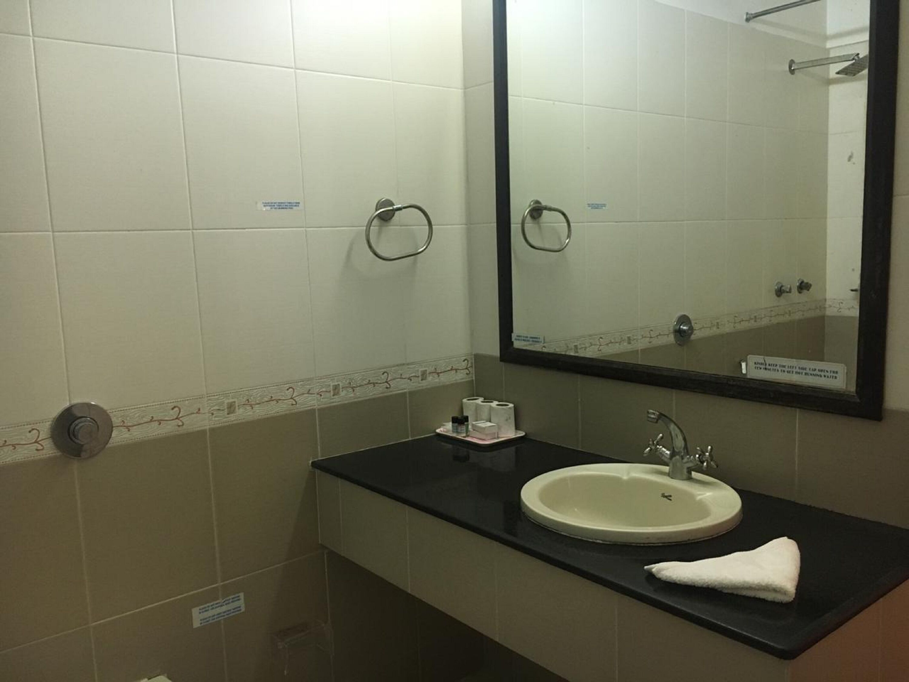 A bathroom with a sink, mirror, towel, and toilet paper.
