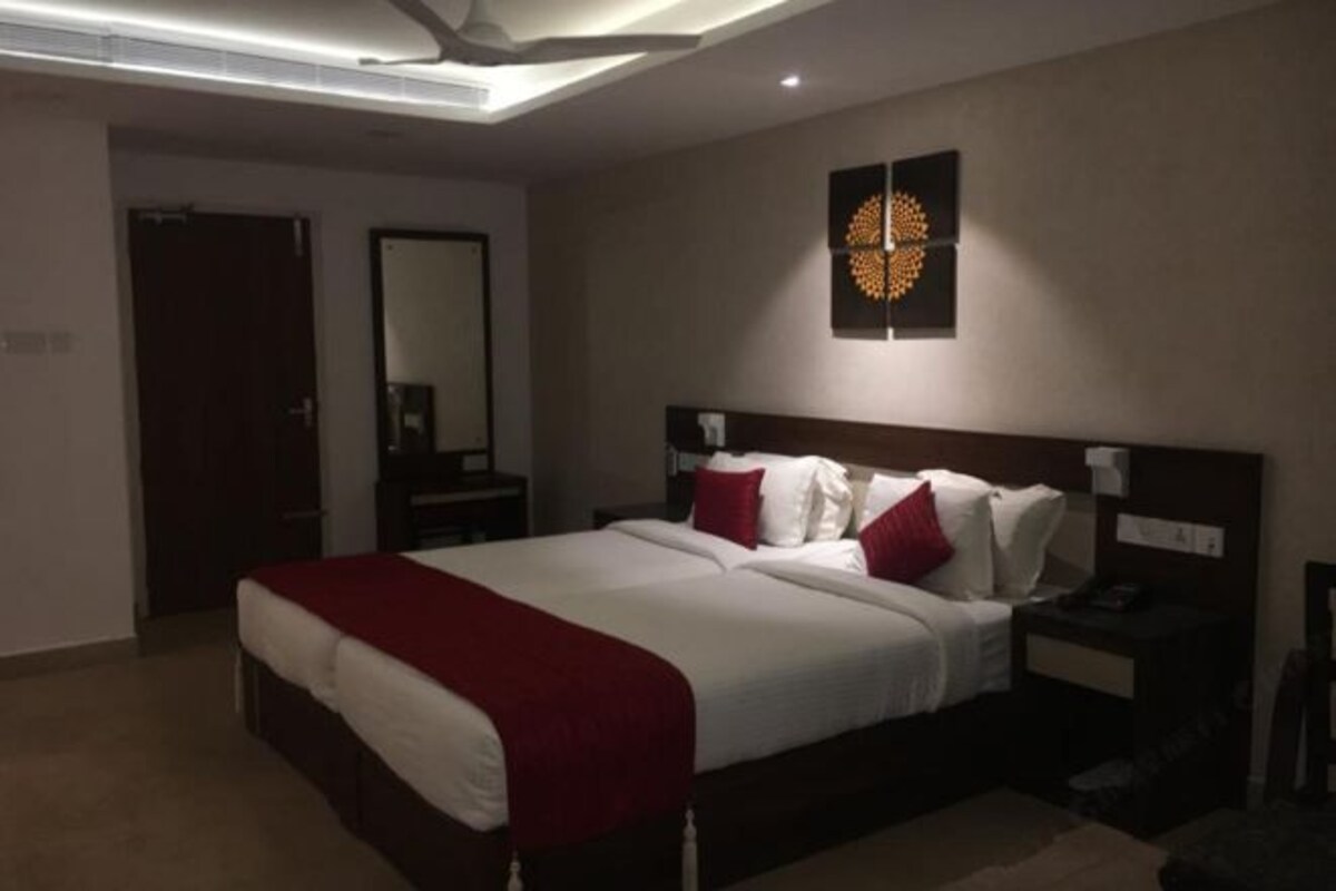 Una habitación de hotel moderna con una cama grande, una mesita de noche y una obra de arte colgada en la pared.