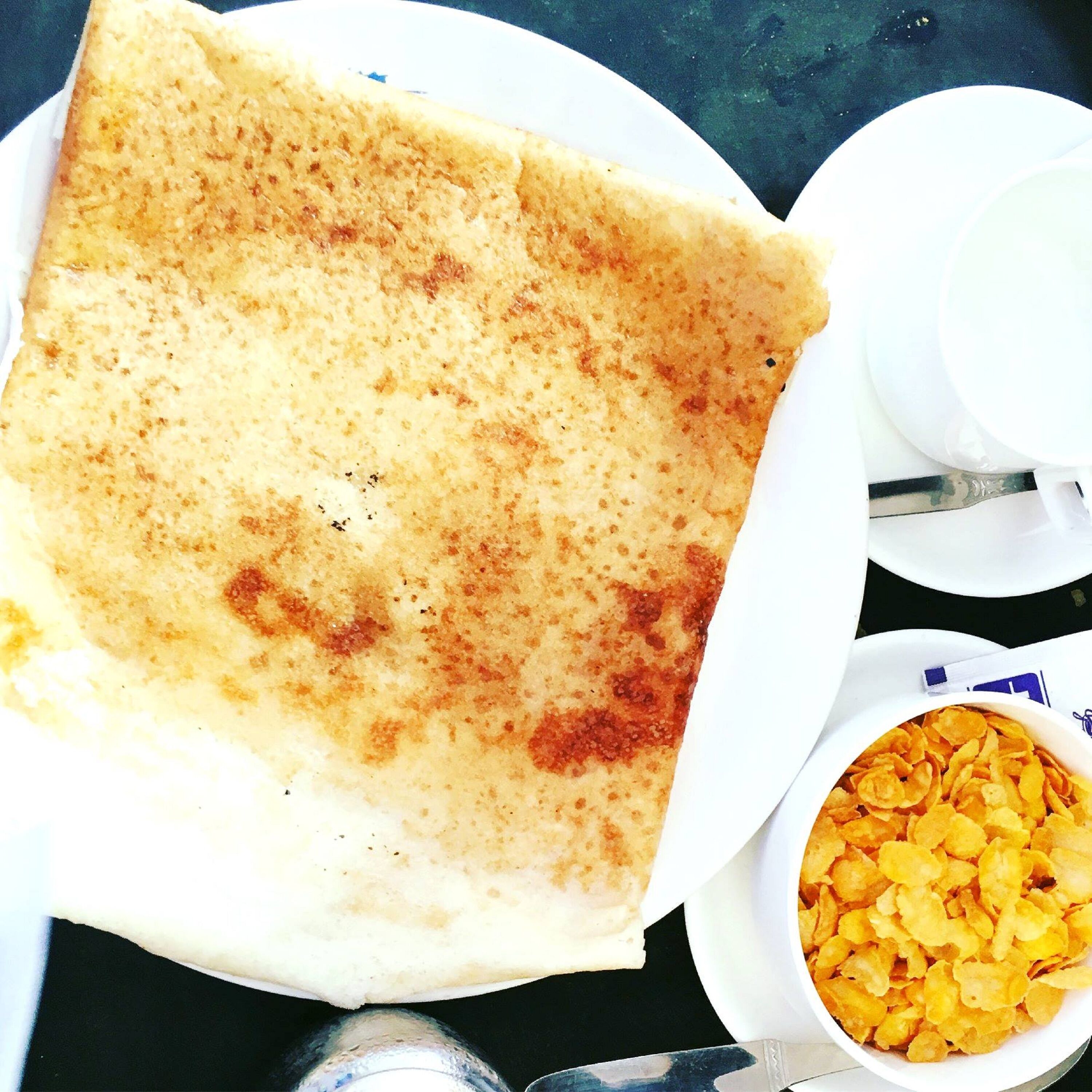 Una crepe sobre un plato blanco con un tazón de copos de maíz a un lado.