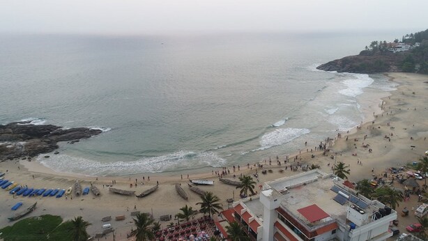 A beach with boats, umbrellas, and people. - Hotel Sea Face (Neyyattinkara)