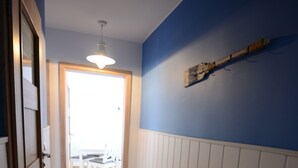 A hallway with wooden flooring, white wainscoting, and a blue accent wall. - Victus Apartamenty - Marina (Sopot)