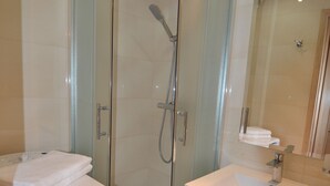 A modern bathroom with a glass-enclosed shower, a white sink, and a mirror. - Victus Apartamenty - Marina (Sopot)
