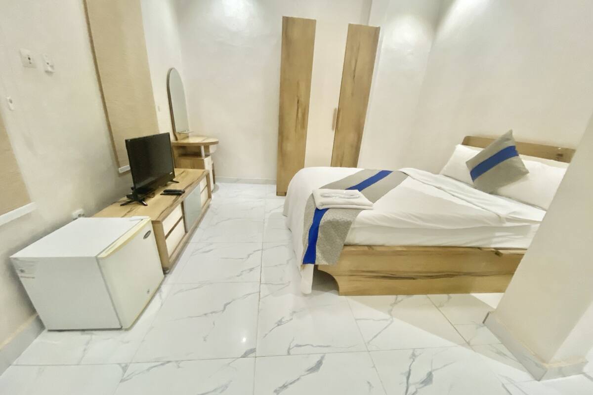 A hotel room with a bed, a TV, a desk, and a wardrobe.