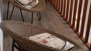 Una escalera con sillas de mimbre y baranda de madera.