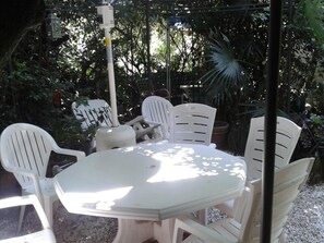An outdoor patio with a white table and chairs, surrounded by greenery. - Domaine des Plantes (Rennes)