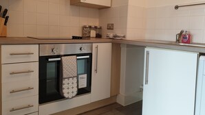 Eine moderne Küche mit weißen Schränken, einem eingebauten Backofen und einer Arbeitsplatte mit einer Spülmittelflasche.
