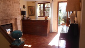 Una habitación con chimenea, un mostrador de recepción de madera, una ventana con cortinas y una lámpara.