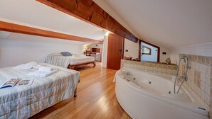 A bedroom with two beds, a large bathtub, wooden beams, and a wooden floor. - Villa Monte Enrico - With Pool (Camporosso)