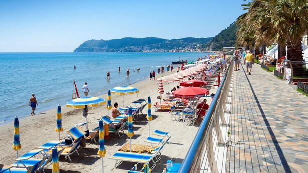 A beach with rows of sun loungers and umbrellas, a walkway, and a view of the sea and hills in the background. - Villa Monte Enrico - With Pool (Camporosso)