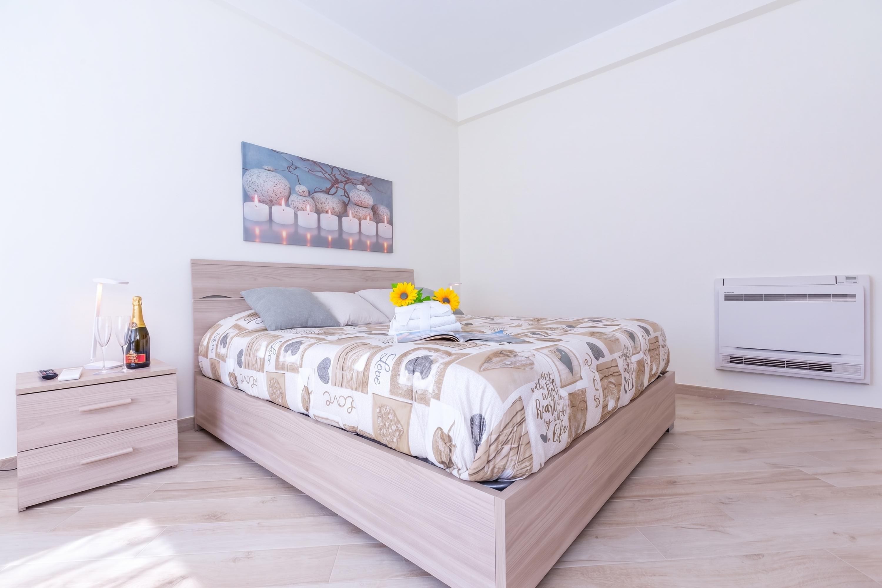 Un dormitorio con una cama de madera, una mesita de noche, un aire acondicionado montado en la pared y un cuadro sobre la cama.
