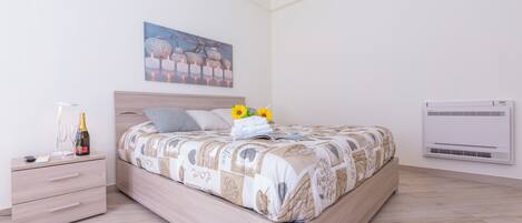 A bedroom with a bed, a nightstand, a wall-mounted air conditioner, and a painting.