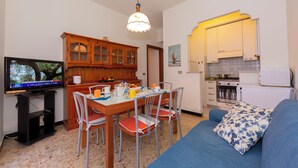 A compact living space with a dining area, kitchenette, and a television.