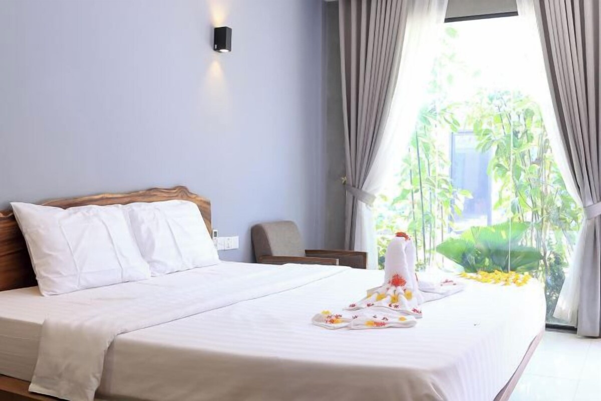 A neatly made bed with white linens and a floral arrangement on the side.