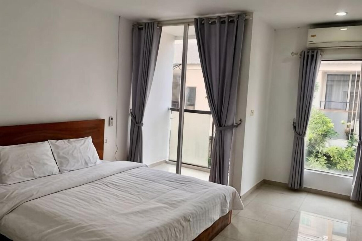 A bedroom with a bed, a sliding glass door, and a view of the outside.