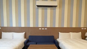 A hotel room with two single beds, a central sofa, a wooden table, and an air conditioning unit mounted on the wall. - Small Ryukyu Loju sunrise Inn (Liuqiu)