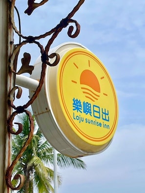 A circular sign with a sunrise illustration and text indicating 'Loju Sunrise Inn'. - Small Ryukyu Loju sunrise Inn (Liuqiu)