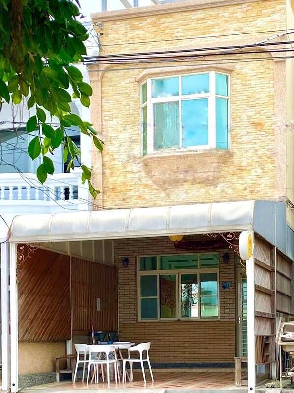 A two-story building with a covered patio area featuring a table and chairs.