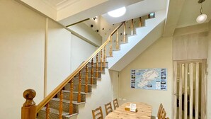 A dining area with a wooden table and chairs, a staircase with wooden balusters, and a map on the wall. - Small Ryukyu Loju sunrise Inn (Liuqiu)