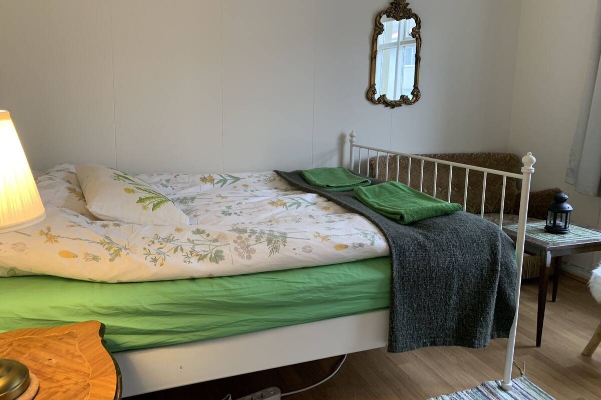A neatly made bed with floral bedding, a bedside lamp, and a small table with a lantern.