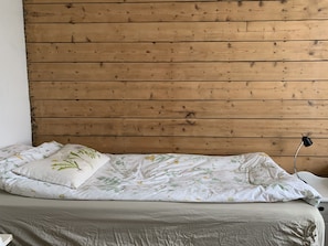 Cama de solteiro com roupa de cama florida e cabeceira de madeira.