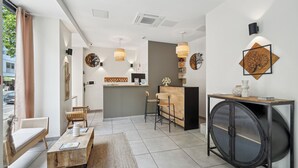 A modern hotel lobby with a reception desk, seating area, and a large round table. - Hotel Le National Clichy Paris (Clichy)