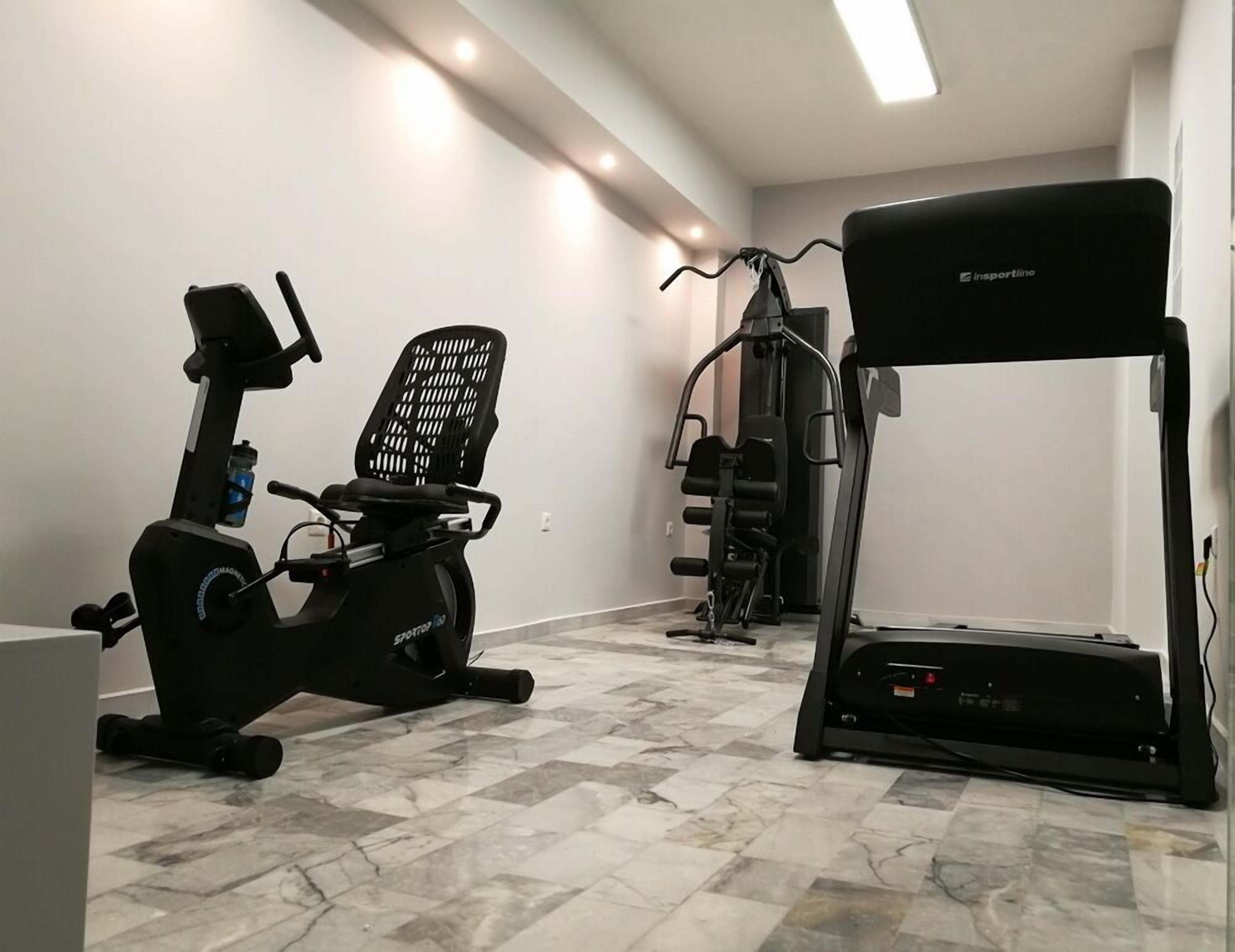 A home gym with an elliptical, a stationary bike, and a treadmill.