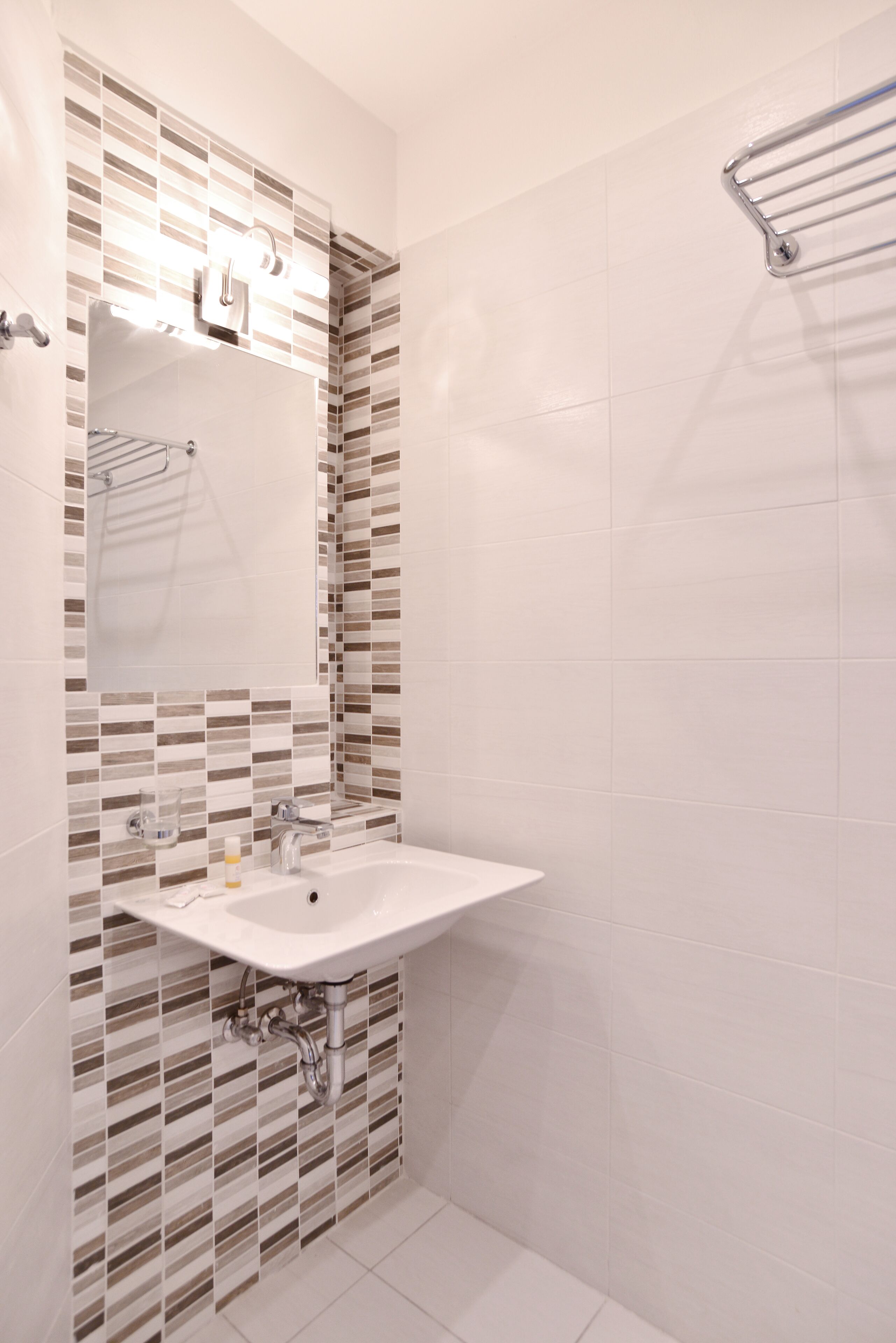 A bathroom with a white sink, a mirror, and a shower area.